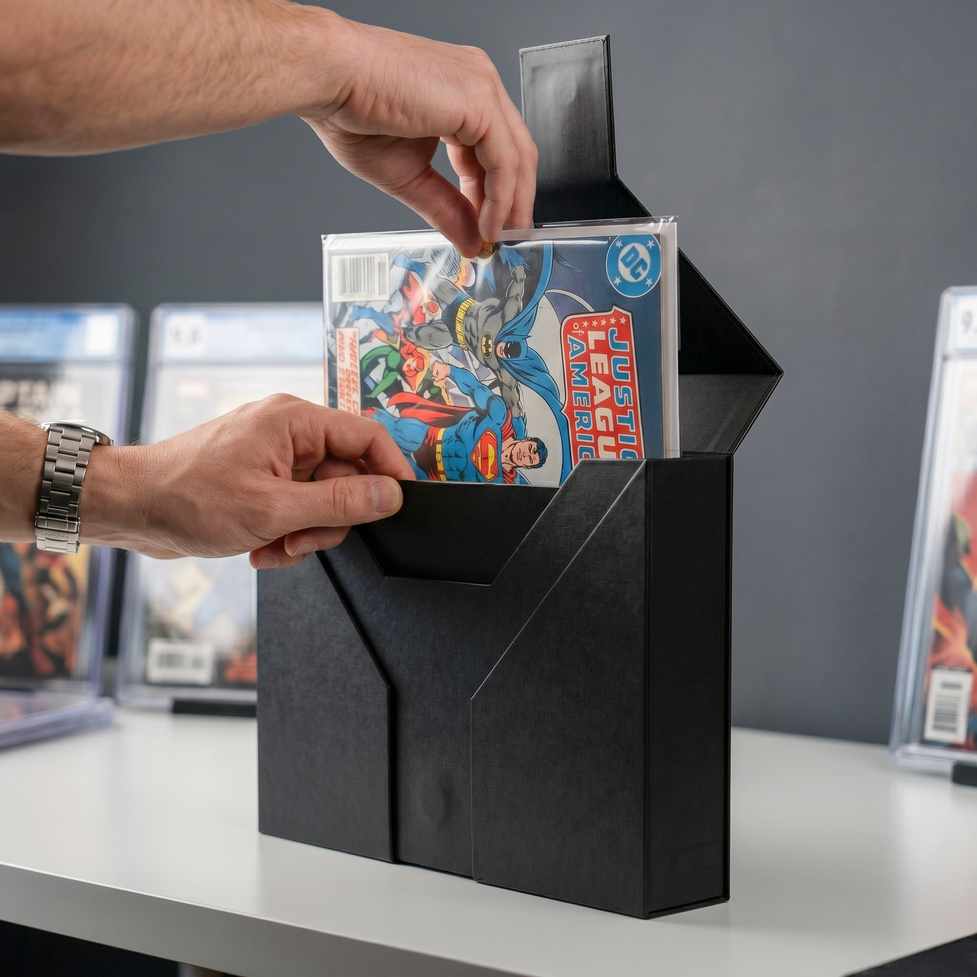 Person placing a comic book into a black display case with other comic books in the background.